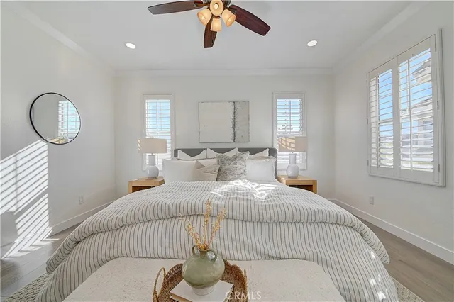 a bedroom with a bed ceiling fan and a wooden floor