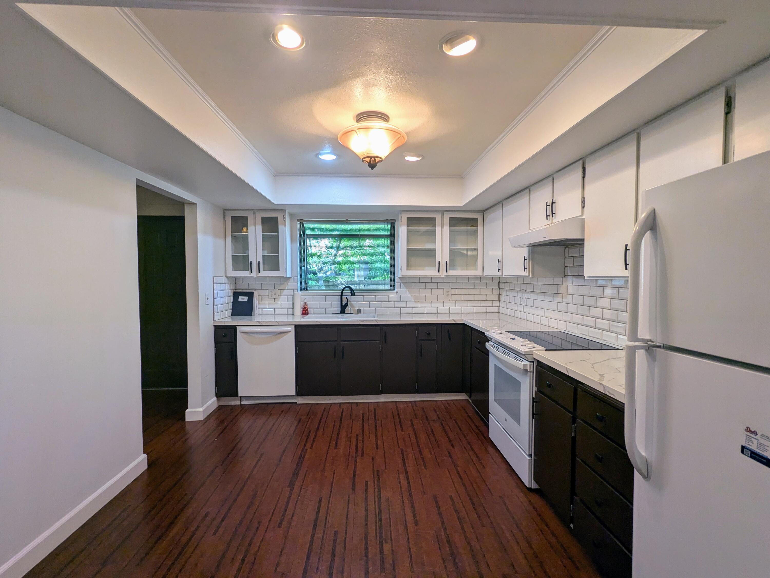 1974 Bechelli Lane Redding, CA 96002 - Photo 17 of 49 a large kitchen with a refrigerator a sink dishwasher a stove and white countertops with wooden floor