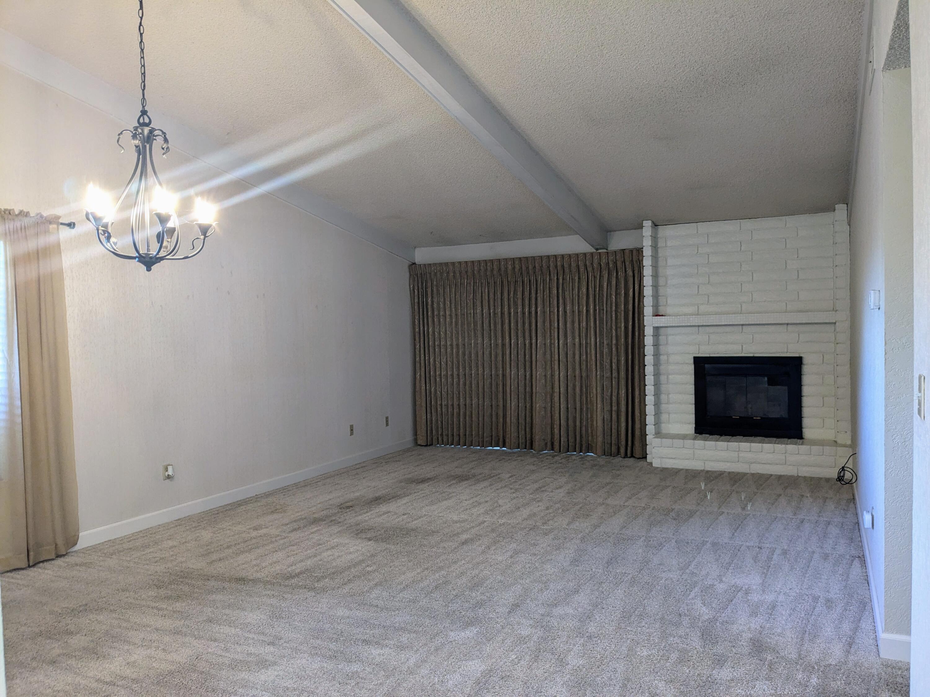 1974 Bechelli Lane Redding, CA 96002 - Photo 22 of 49 an empty room with a fireplace and chandelier