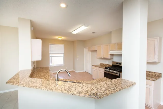 a kitchen with kitchen island granite countertop a stove a sink a refrigerator and window