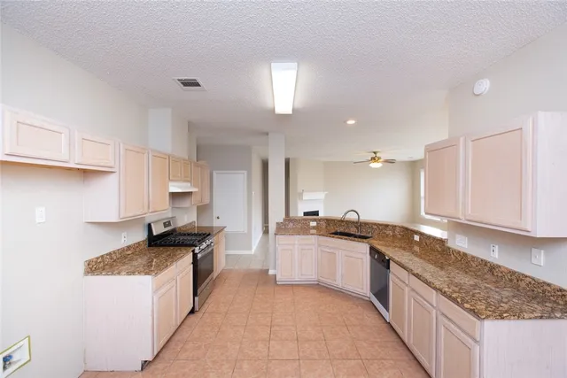 a large kitchen with granite countertop a sink and dishwasher a stove top oven with wooden floor