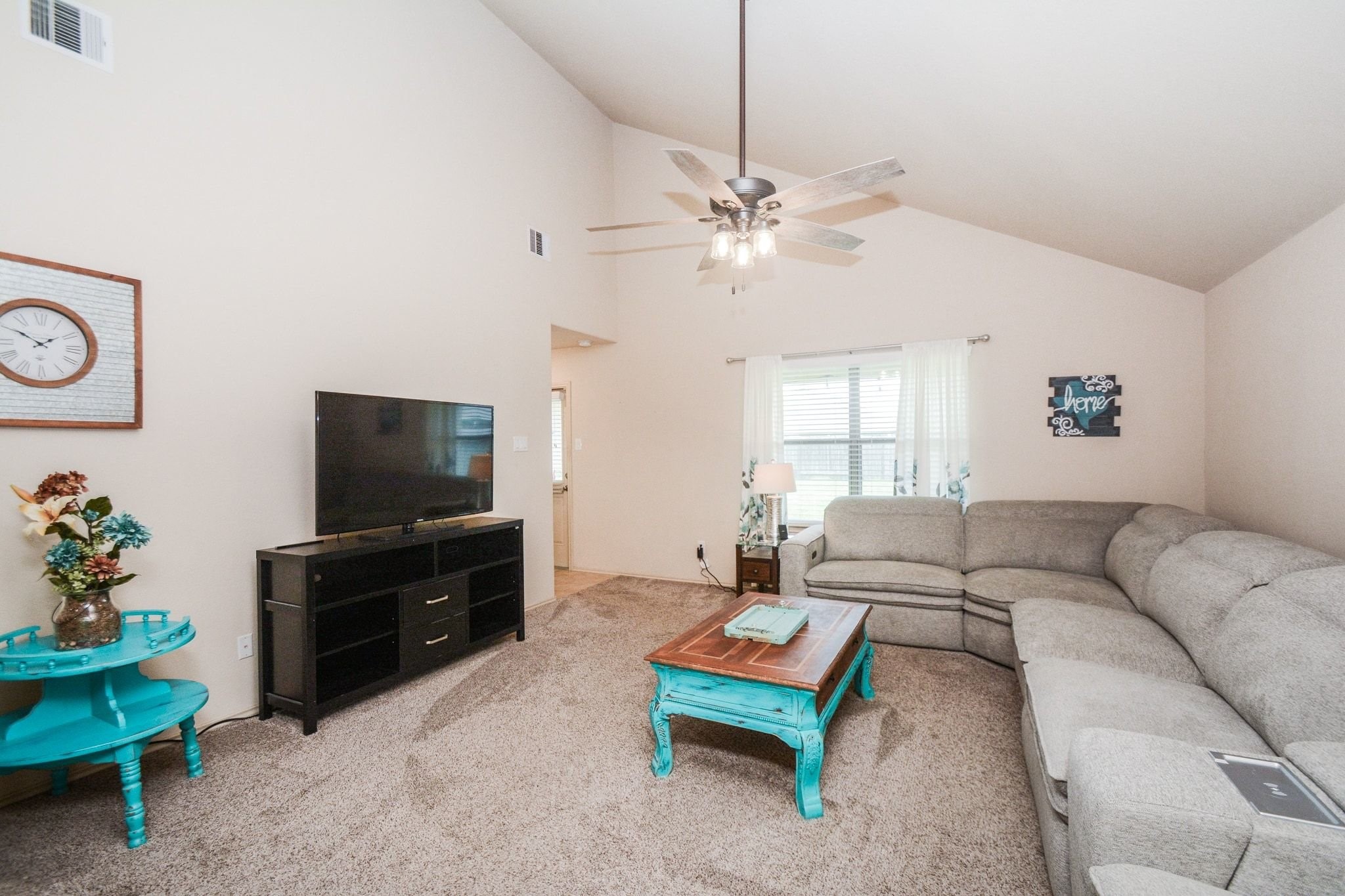 23318 Dukes Run Drive Spring, TX 77373 - Photo 18 of 41 Spacious living room with vaulted ceiling, neutral walls, and carpeted flooring. With room enough for a large sectional sofa, ceiling fan, and a TV setup. Natural light streams in through the window, complementing the cozy ambiance.