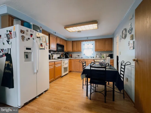 a kitchen with granite countertop a refrigerator a sink dishwasher a stove and a refrigerator with wooden floor