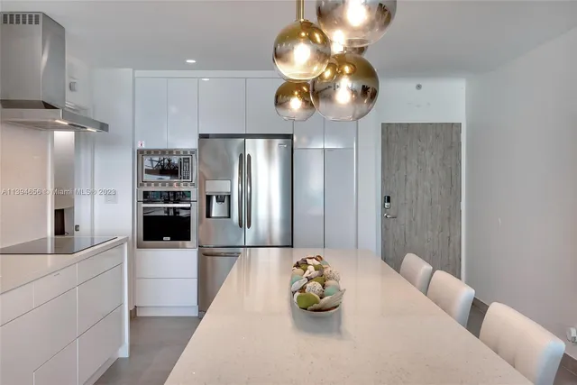 a kitchen with stainless steel appliances kitchen island granite countertop a refrigerator a stove and a sink