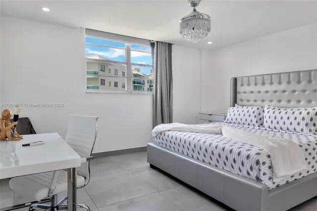 a large bed sitting in a bedroom next to a window and a chandelier