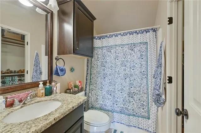 a bathroom with a granite countertop sink toilet and shower
