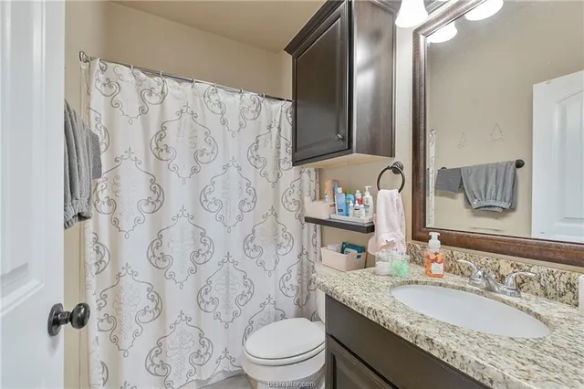 a bathroom with a granite countertop sink a toilet and a mirror