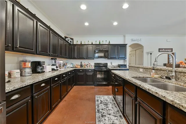a kitchen with granite countertop a sink a counter top space cabinets and stainless steel appliances
