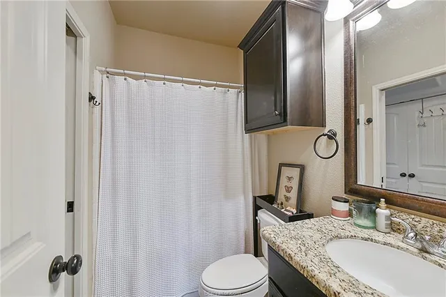 a bathroom with a granite countertop sink vanity mirror and a toilet