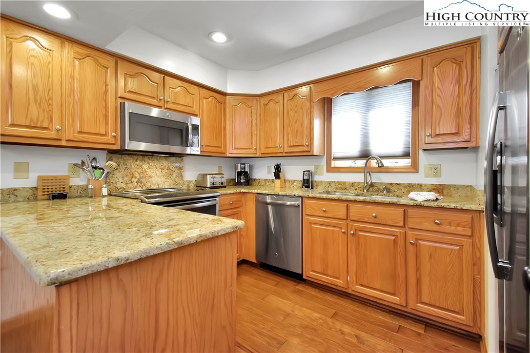 140 Manor View Lane, Unit CASCADES 2 Blowing Rock, NC 28605 - Photo 11 of 25 a kitchen with stainless steel appliances granite countertop a stove a sink dishwasher and a microwave oven with wooden cabinets