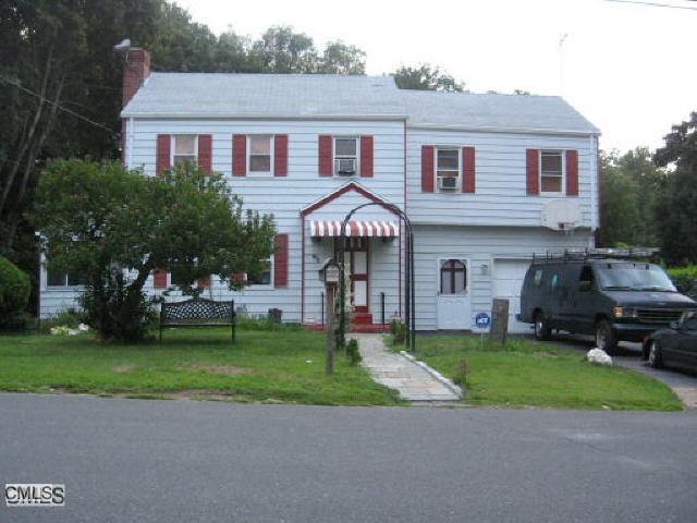 a front view of a house with a garden and trees