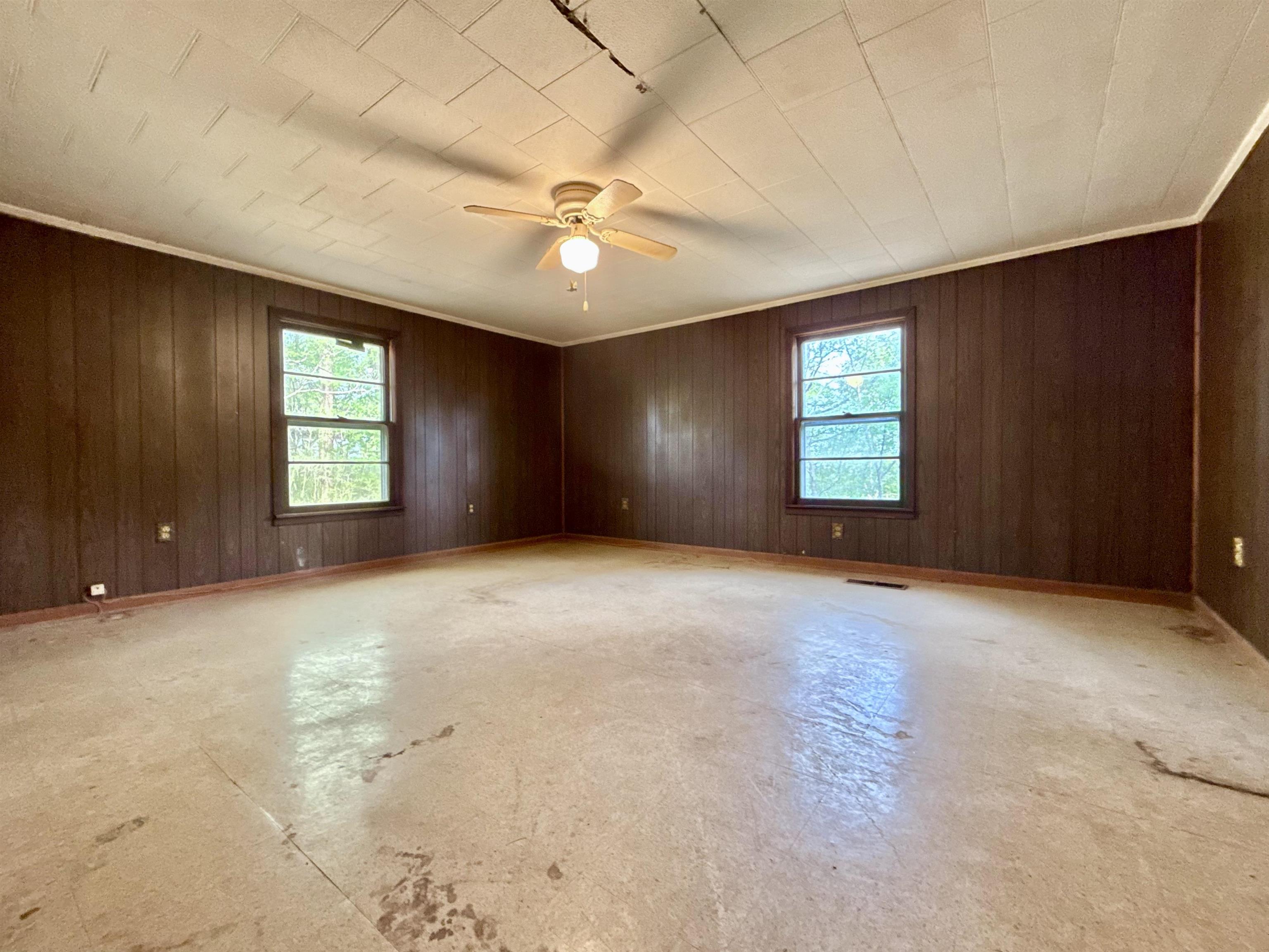 845 Needham Road Drummonds, TN 38023 - Photo 11 of 22 Unfurnished room with healthy amount of natural light, concrete flooring, ceiling fan, wood walls, and ornamental molding