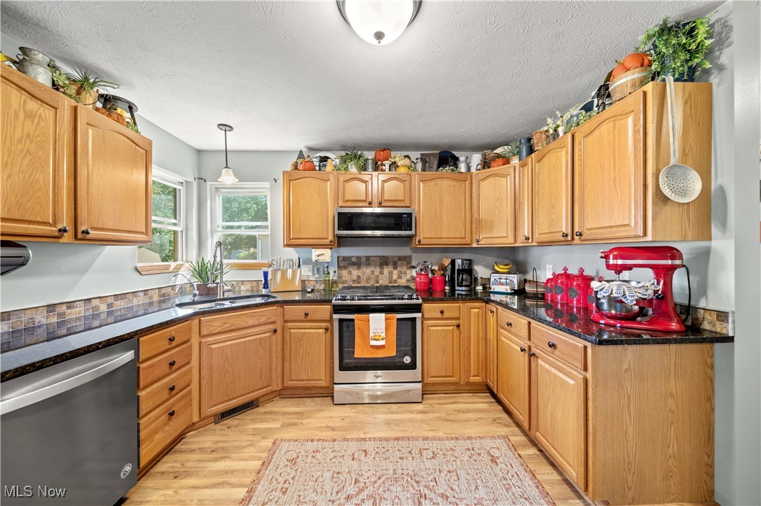 1951 Haines Road Madison, OH 44057 - Photo 11 of 44 Kitchen featuring hanging light fixtures, sink, a textured ceiling, light hardwood / wood-style flooring, and stainless steel appliances