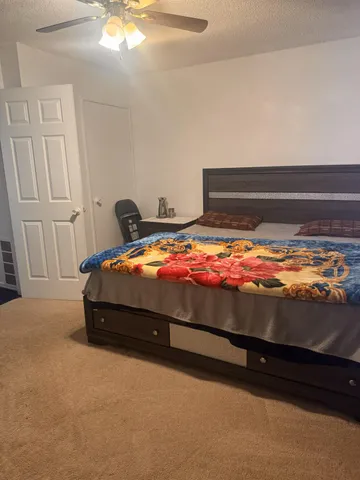 a bedroom with a bed and a chandelier fan