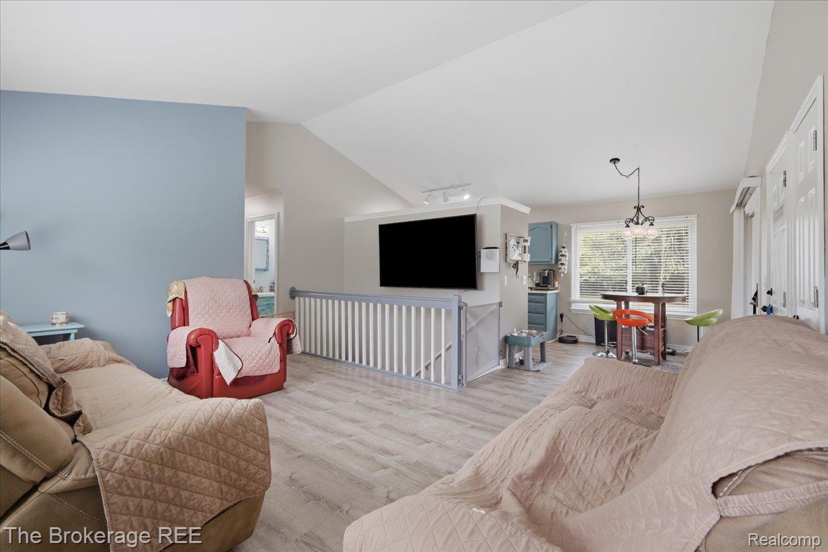 11282 Silver Lake Road Byron, MI 48418 - Photo 2 of 32 Open-concept living area featuring wood-finish flooring, a vaulted ceiling, a built-in media center, and a dining space with a window
