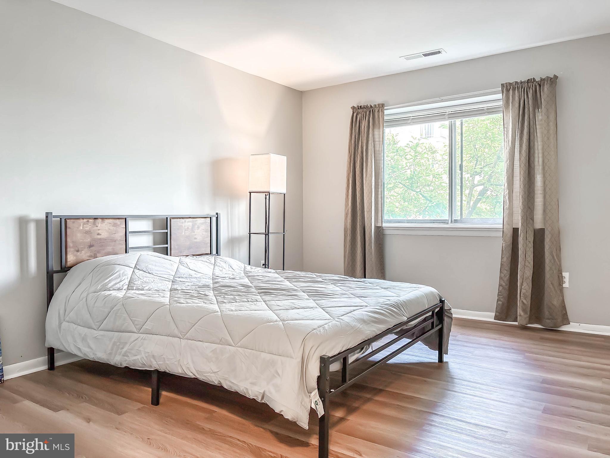 130 Slade Avenue, Unit 414 Baltimore, MD 21208 - Photo 28 of 48 a bedroom with a bed and wooden floor