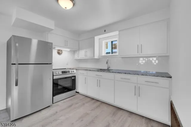 a kitchen with granite countertop a sink stove and refrigerator