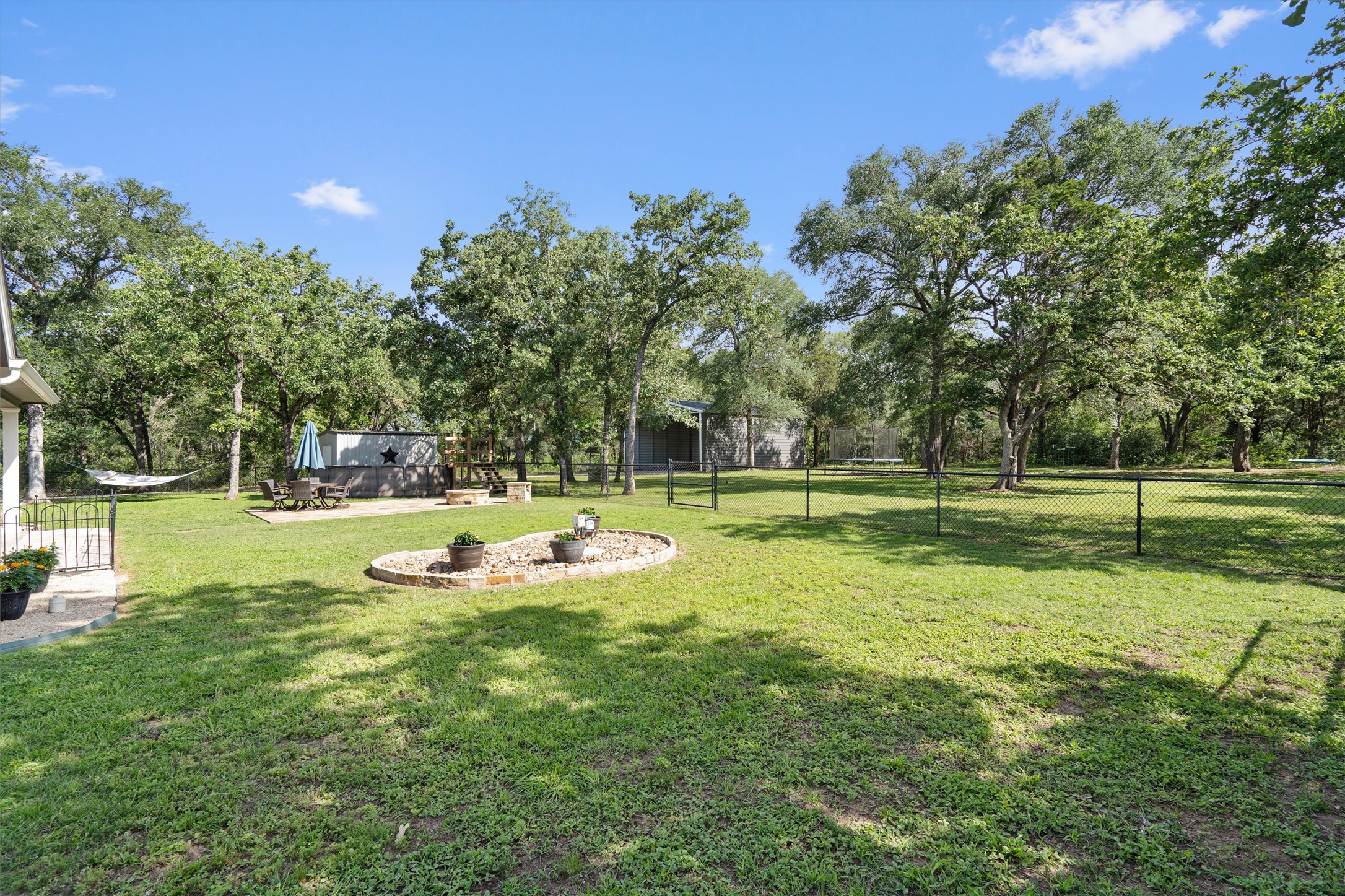 136 Fawn Hollow Elgin, TX 78621 - Photo 35 of 40 Expansive backyard featuring a lush lawn, mature trees, and chain-link fencing