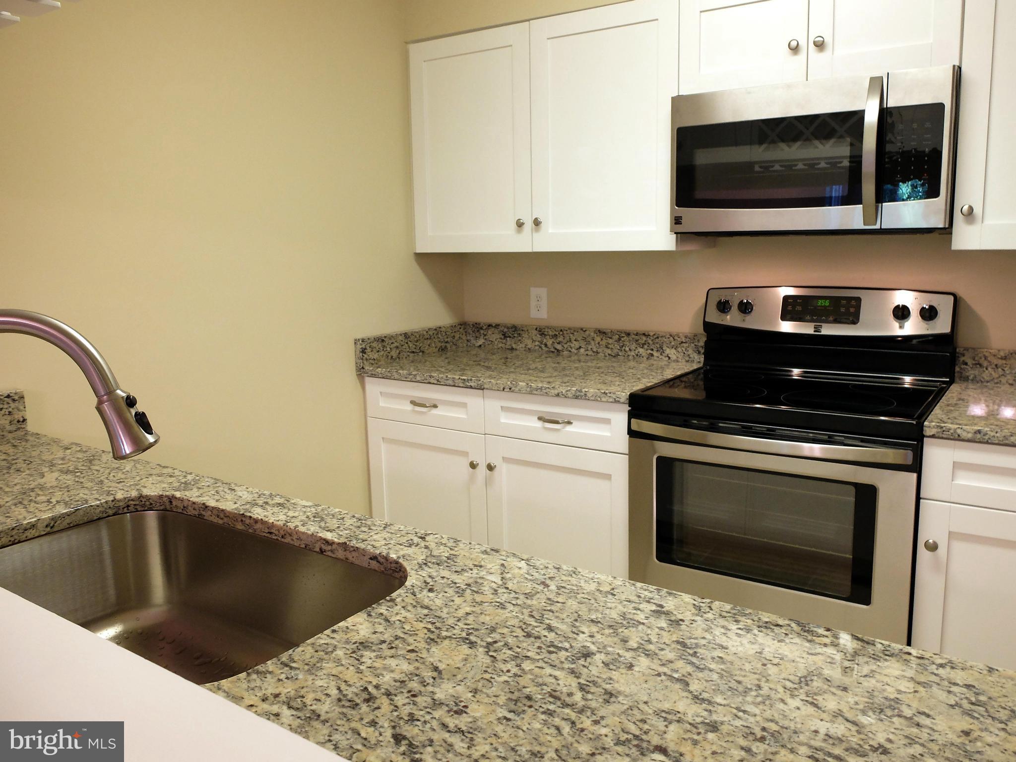 4922 Columbia Road, Unit 585 Columbia, MD 21044 - Photo 14 of 30 a kitchen with a stove and a microwave