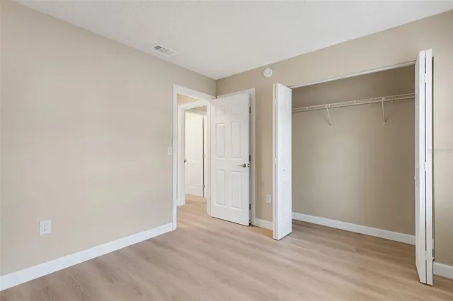 a view of an empty room with wooden floor and closet area