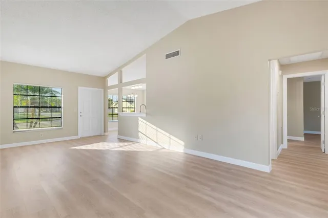 a view of an empty room with wooden floor and a window
