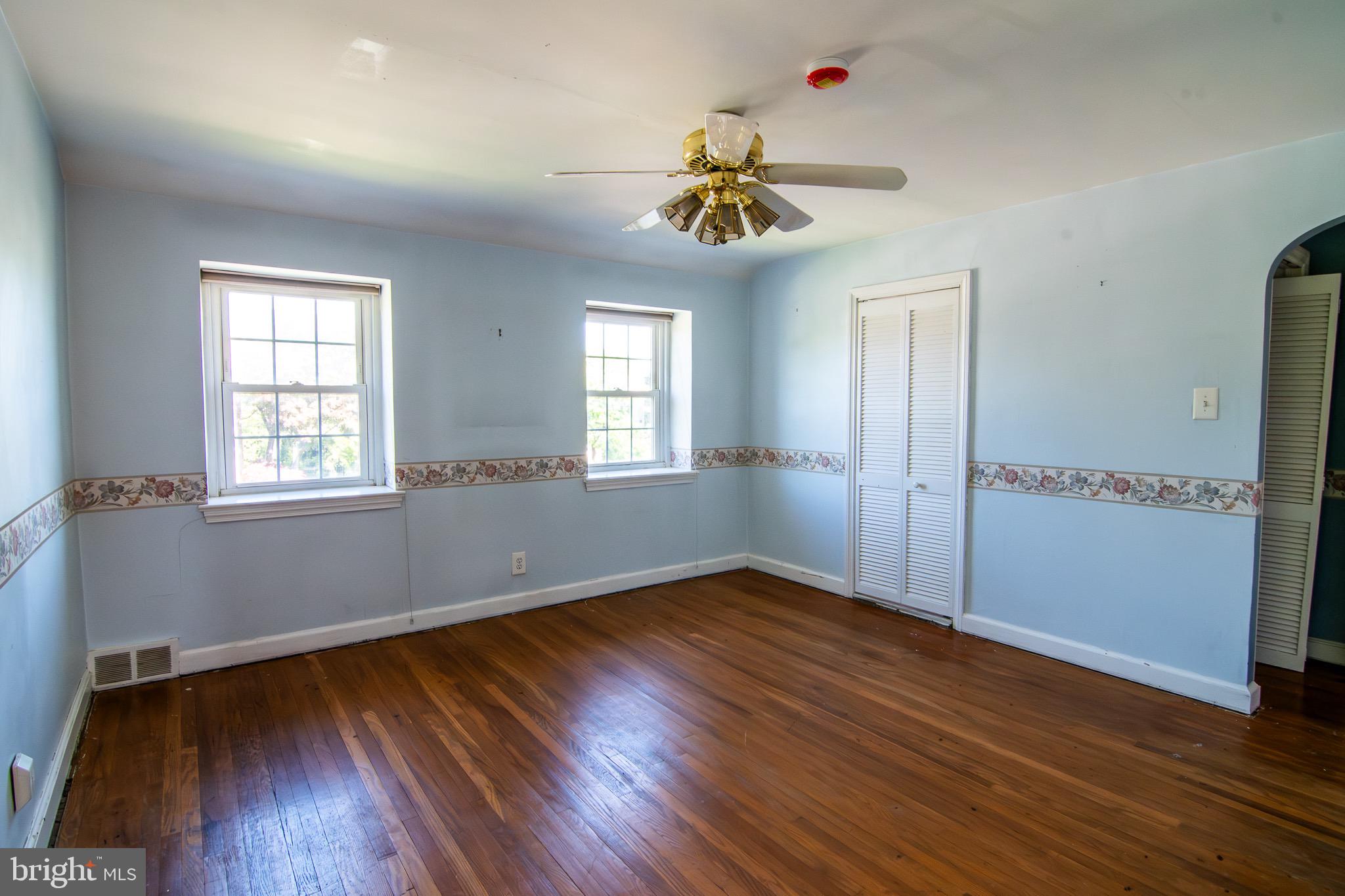 5004 Fairway Road Drexel Hill, PA 19026 - Photo 15 of 29 an empty room with wooden floor chandelier fan and windows