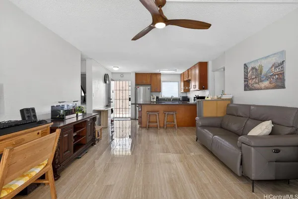 a living room with stainless steel appliances granite countertop furniture wooden floor and a view of kitchen