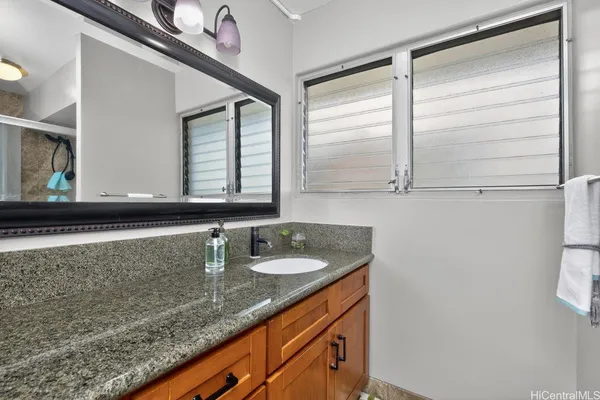a bathroom with a granite countertop sink and a mirror