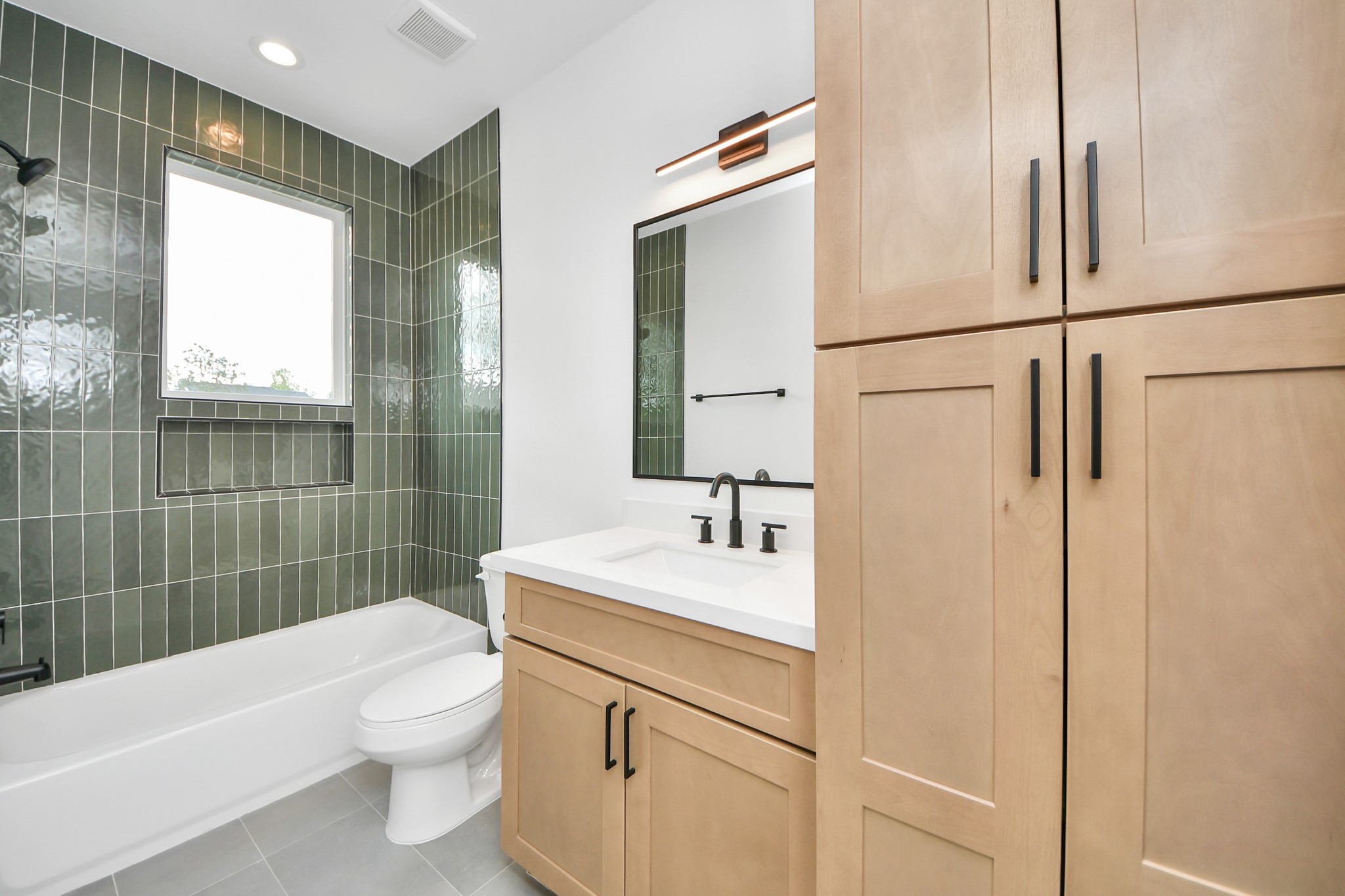 505 Middle Street Houston, TX 77003 - Photo 33 of 46 Discover the elegance of this second full bathroom, featuring sleek green tile, modern fixtures, and ample storage for a touch of luxury and functionality.