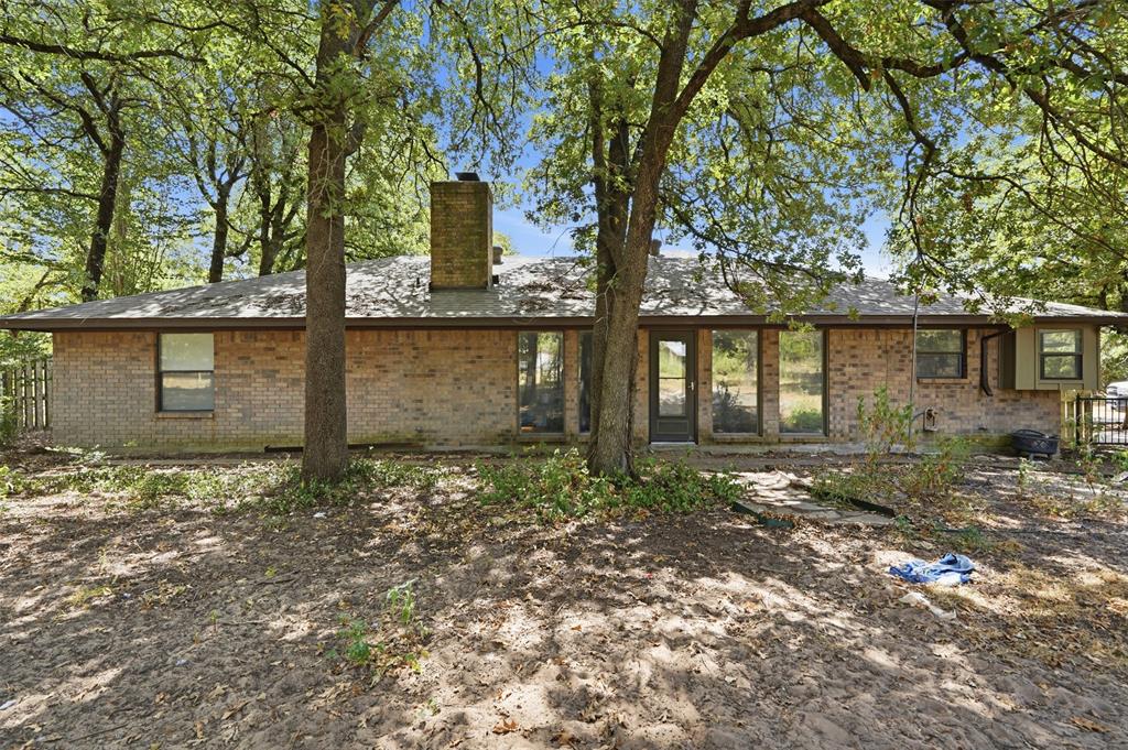 104 Murls Lake Road Weatherford, TX 76085 - Photo 34 of 39 Brick exterior featuring a gabled roofline, multiple windows, a rear entry door, and a chimney