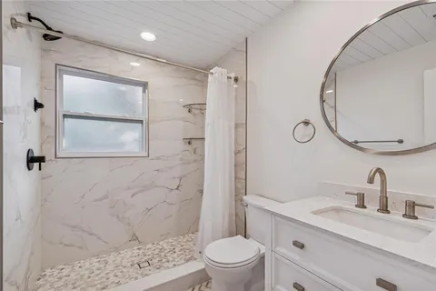 a bathroom with a sink a toilet and shower