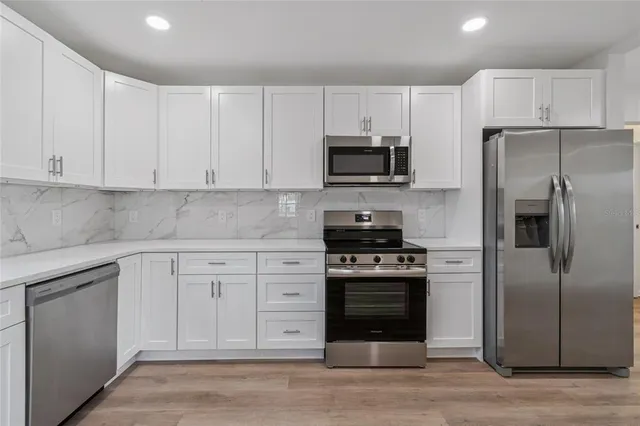 a kitchen with cabinets stainless steel appliances and a counter space