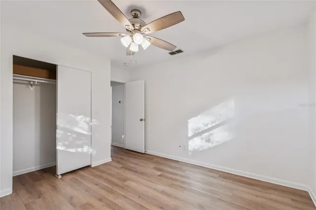 an empty room with wooden floor closet and windows