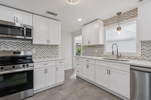 a kitchen with granite countertop white cabinets and stainless steel appliances