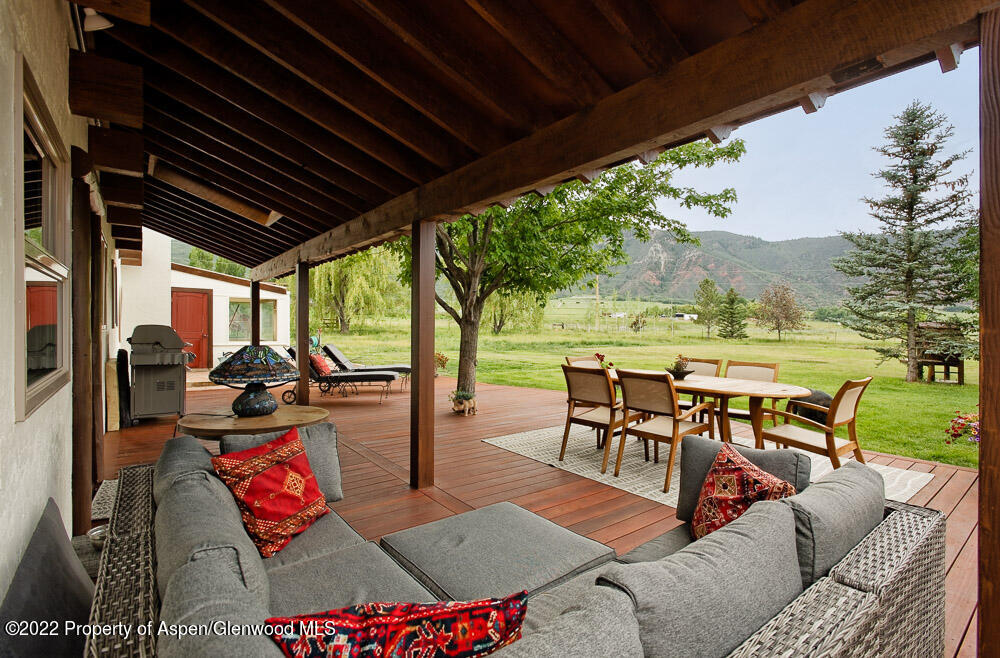 2459 Emma Road Basalt, CO 81621 - Photo 23 of 31 a view of a patio with dining table and chairs with wooden floor and fence