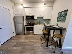 a kitchen with stainless steel appliances granite countertop a refrigerator a stove a sink dishwasher and white cabinets with wooden floor
