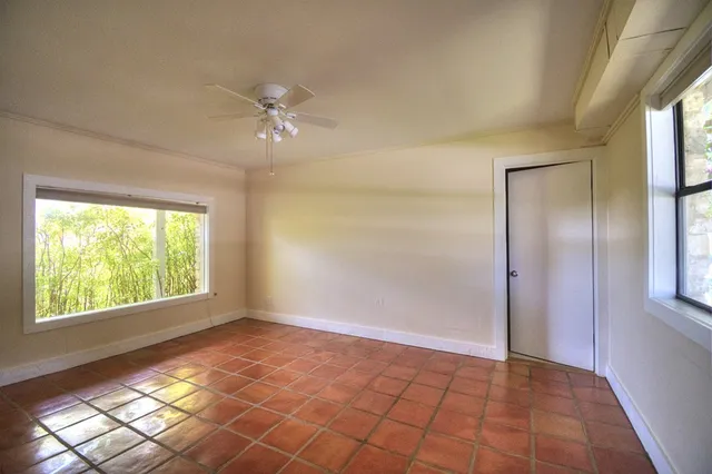 a view of an empty room and window and chandelier fan
