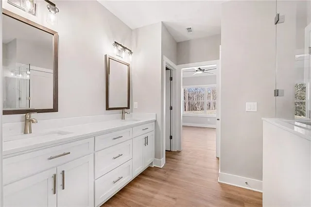 a bathroom with a double vanity sink and mirror with wooden floor