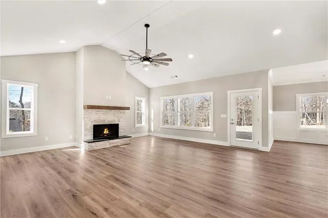 a view of an empty room with wooden floor fireplace and a window