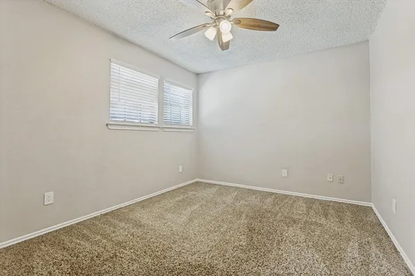 an empty room with a chandelier fan and windows