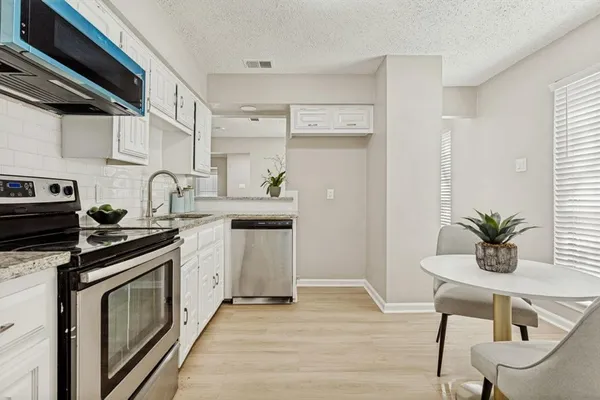 a kitchen with stainless steel appliances a white stove top oven and white cabinets