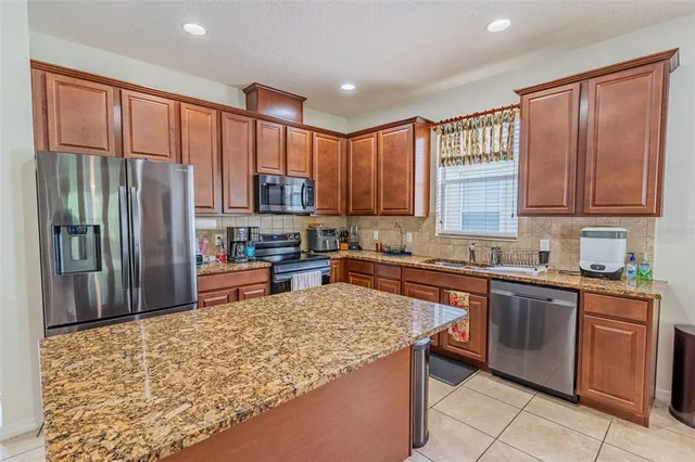 a kitchen with stainless steel appliances granite countertop a refrigerator stove top oven and large window