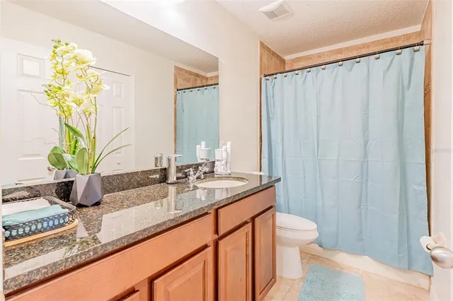 a bathroom with a granite countertop sink a toilet and with mirror