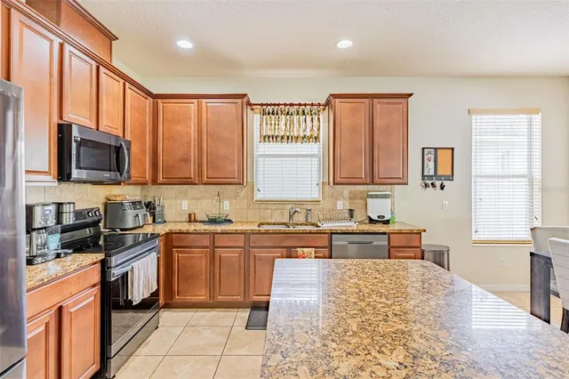 a large kitchen with granite countertop a stove top oven a sink a window and dining table