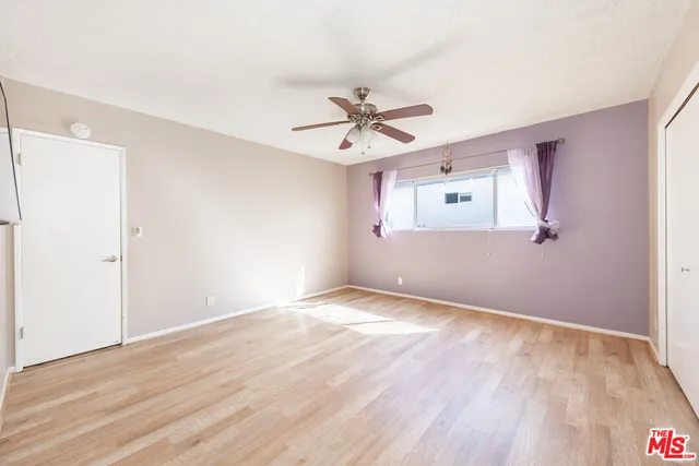 a view of an empty room with window and wooden floor
