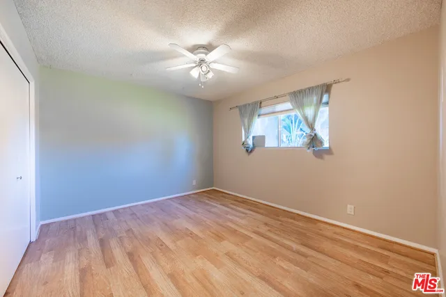 an empty room with wooden floor chandelier fan and windows