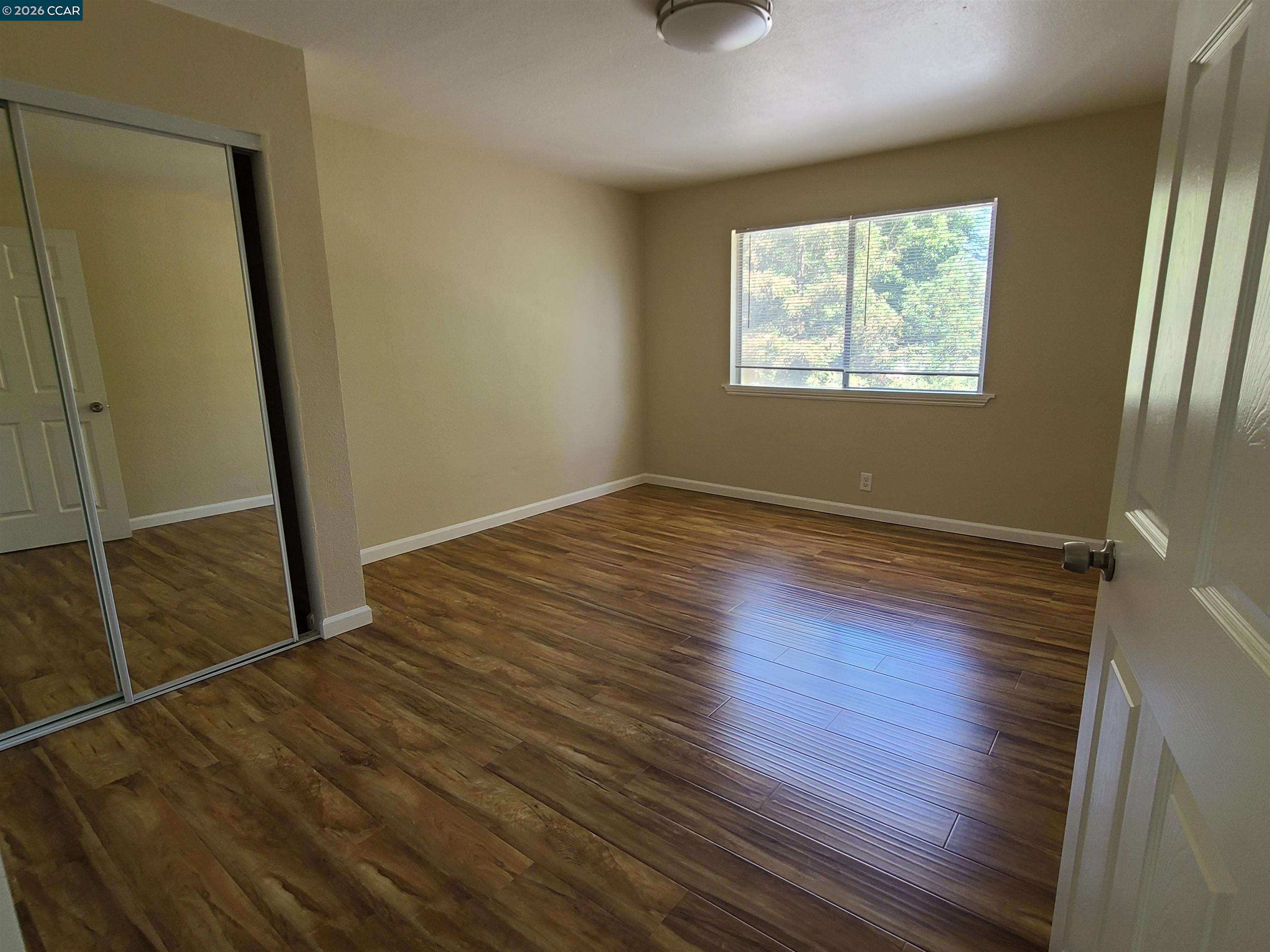 1906 Queens Road, Unit 8 Concord, CA 94519 - Photo 2 of 6 an empty room with wooden floor and windows