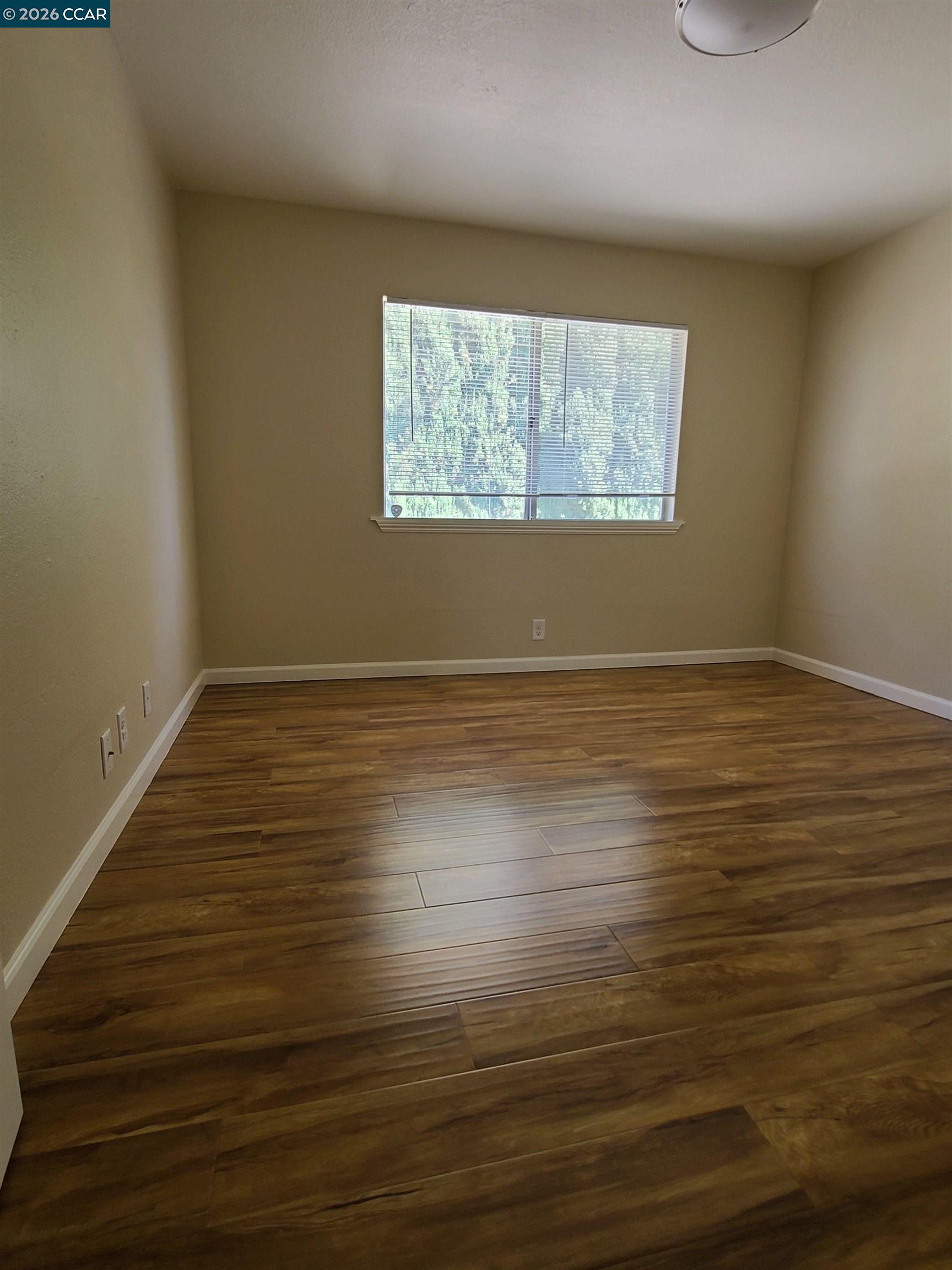 1906 Queens Road, Unit 8 Concord, CA 94519 - Photo 3 of 6 a view of an empty room with wooden floor and a window