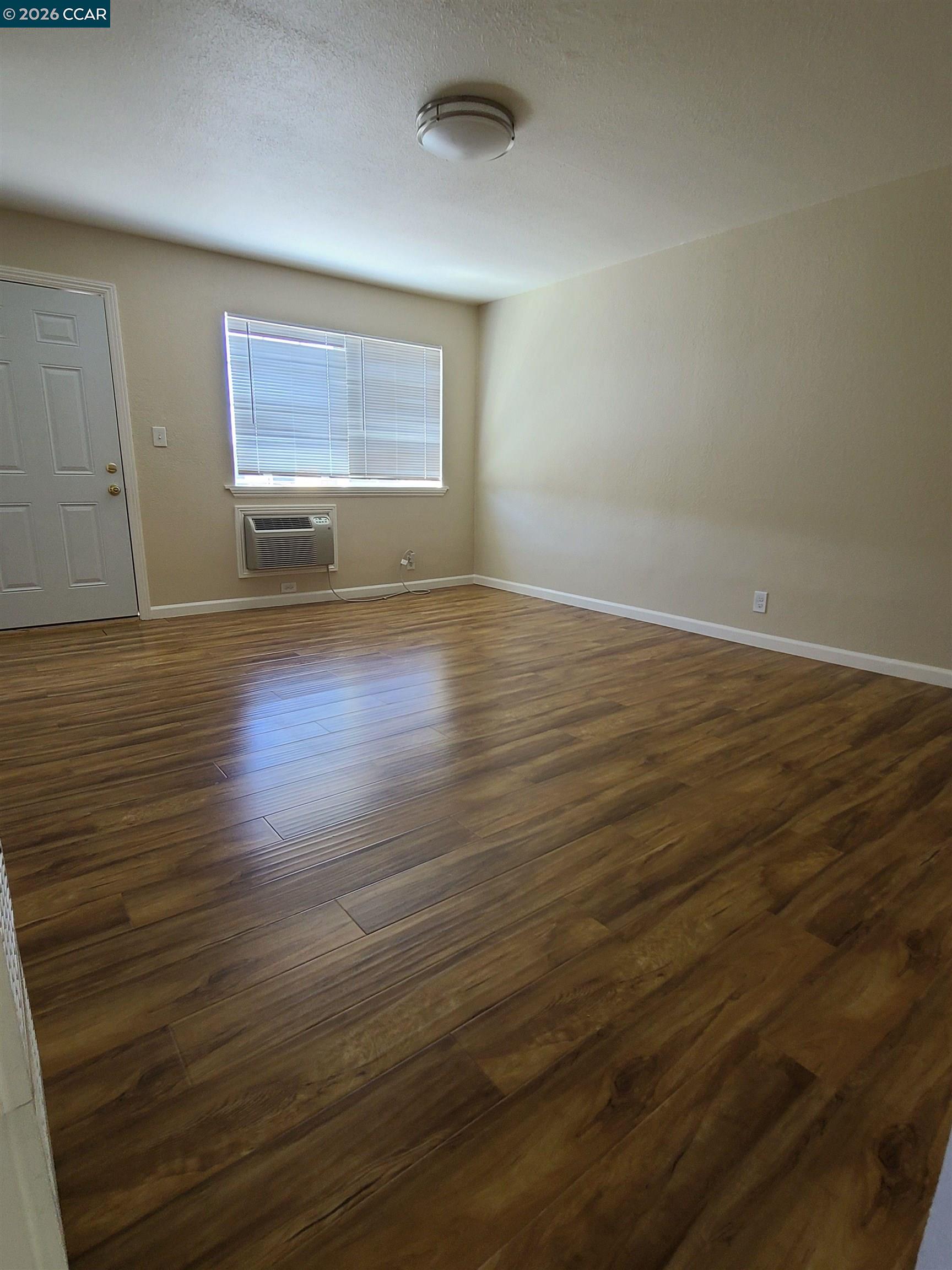 1906 Queens Road, Unit 8 Concord, CA 94519 - Photo 5 of 6 an empty room with wooden floor and windows