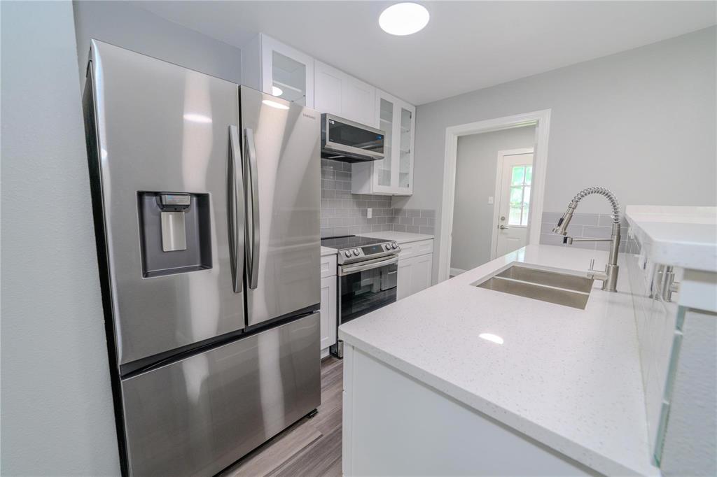 809 Wilcox Street McKinney, TX 75069 - Photo 9 of 26 Kitchen with stainless steel appliances, glass fronted cabinets, light stone countertops, and white cabinetry